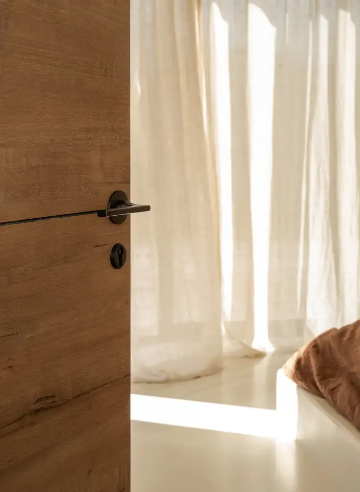 Porte en bois entrouverte sur une chambre baign&eacute;e de lumi&egrave;re