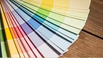 Nuancier de couleurs pastel ouvert en éventail sur un plancher en bois